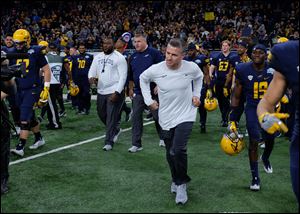 Toledo head coach Jason Candle runs onto the field to greet Akron head coach Terry Bowden seconds after  winning the MAC Championship football game at Ford Field in Detroit.