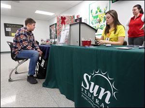 Clay student Greg Faneuff, left, signs up for a direct deposit checking account while Senior Taytem Rew, center, Sun/Clay CU volunteer, sits at the cashbox at Clay High School.