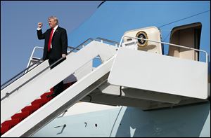 President Donald Trump gestures to a cheering crowd on the tarmac as he arrives on Air Force One at Palm Beach International Airport, in West Palm Beach, Fla., on Friday, Dec. 22.