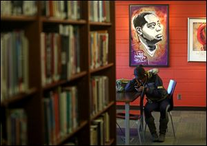 Taylor Lewis, of Toledo, relaxes on her phone, at the Art Tatum African American Resource Center at the Kent Branch Library in Toledo on Friday, December 8.