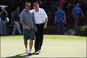 President Donald Trump walks with Gene Gibson, commanding officer at Coast Guard Station Lake Worth Inlet, as he meet with members of the U.S. Coast Guard, who he invited to play golf, at Trump International Golf Club on Friday.