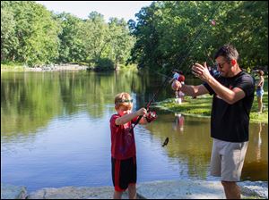 Andrew Posadny of Sylvania gets a fishing lesson from his dad Chris Posadny at Mallard Lake in Oak Openings Preserve Metropark.     