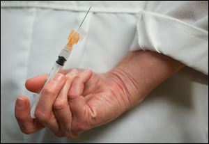 Nurse practitioner Amy Spangler holds a flu shot behind her back at Mercy Health in Sylvania, Ohio Jan. 11.