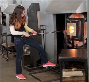 Art After School participant Mikenzie Dayton, 15, fires the glass piece she has been working on in the furnce. Students were able to take part in a glassblowing class through the Toledo Art Museum's Art After School program.