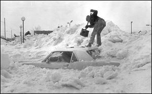 Jerry Ludwig of Toledo tries to dig his car out of a snow bank at Glynbyrne Shopping Center parking lot after the blizzard of 1978. The vehicle was buried by the snow plows.