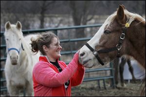 Anna Mueller, Assistant Director of Starry Skies Equine Rescue, embraces a horse affectionately renamed Freddy Eddy Flintstone Thursday at the center near Ann Arbor.