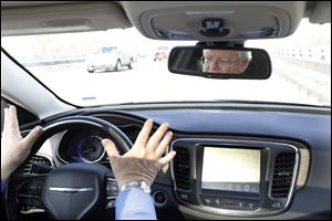 Dave Hobbs, Lead Training Product Developer with Delphi, removes his hands from the steering wheel to demonstrate autonomous elements of a Chrysler 200.