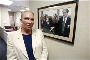 Lucas County Prosecutor Julia Bates poses in front of a photo hanging on the Lucas County Prosecutor's Office wall from the Cook brothers case in 2000 at the Lucas at the Lucas County Courthouse in Toledo on Monday, January 29, 2018. 