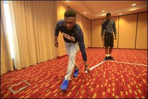 Head managers Deshaun Cole, front, and Brandon Jackson lay down tape markings similar to a basketball court so the team can walk through plays in the hotel ballroom prior to the game against Ball State.