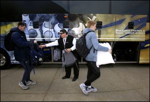 Tad Dunlap with Blue Lakes Charter, center, collects bags to stow for Nate Navigato, left, and Jaelan Sanford before they board the bus on the way to Ball State.