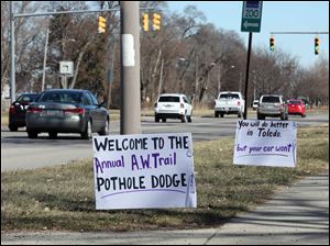 Signs posted by someone concerning the numerous potholes that dot the Anthony Wayne Trail greet motorists on the Trail near Glendale Avenue.