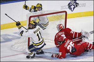 Michigan's Brendan Warren celebrates after scoring on Boston University's Jake Oettinger during the second period of the NCAA northeast regional championship hockey game in Worcester, Mass.