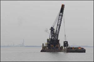 A crane on a barge dredges Lake Erie near the Toledo shipping channel in 2015. A plan by the U.S. Army Corps of Engineers to dump dredged material into open water in western Lake Erie’s North Maumee Bay has met with resistance from some.