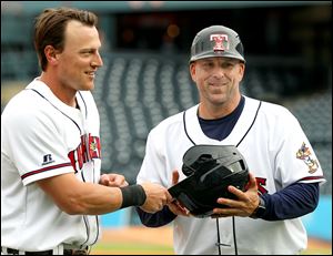 Jim Adduci hands his batting helmet to Mud Hens manager Doug Mientkiewicz during a game earlier this season. Mientkiewicz closed the Toledo clubhouse before the team's game against Louisville Saturday.