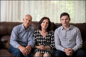 Rustem Kazazi, left, sits at home with wife, Lejla, and son Erald in Parma Heights, Ohio.