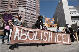 Protesters display a sign that reads “Abolish ICE” during a rally in front of the Immigration and Customs Enforcement facility in Los Angeles on Monday.