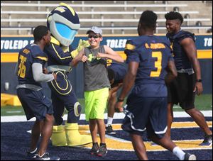 Dylan Baumgartner, 12, who will be attending Elmhurst Elementary, after scoring a touchdown during the University of Toledo’s fifth annual Victory Day. University of Toledo players are, from left, Desmond Bernard, Diontae Johnson, and Reggie Gilliam.