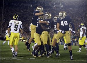 Notre Dame's Nicky Baratti, second from right, is congratulated by teammates after intercepting a pass intended for Michigan's Drew Dileo (9) during the first half of a September, 2012 game in South Bend, Ind.