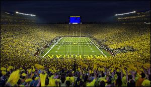 Michigan fans wave pom-poms before a September, 2011 game against Notre Dame in Ann Arbor, Mich. This is the first ever night game to be played at Michigan Stadium.