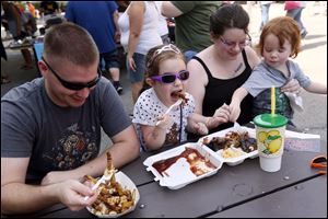 Jordan and Kayla Colburn of Monroe eat poutine and barbecue with their kids Elaina, 4, center, and Dorian, 3, right, during the 7th Annual Labor Day Barbecue Festival Saturday, September 1, 2018, in downtown Monroe. Organizers were expecting about 3,000 people to attend the festivities, which included food and live music.