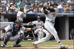 Detroit Tigers' Victor Reyes hits an RBI double as New York Yankees catcher Austin Romine, left, looks on.