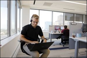 Caleb Parlette, an Electronic Services Specialist, works near the windows at the new headquarters of Directions Credit Union in the Tower on the Maumee.