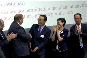 Toledo Mayor Wade Kapszukiewicz, 2nd from left, shakes hands with Topia CEO Hideki Sasaki during a ribbon cutting for Toledo-based company TPAM, a Japanese auto parts subsidiary of Topia.