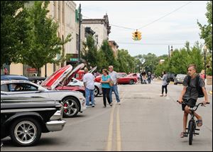 Eli Olmstead, 13, of Fostoria rides his bike on Main Street and checks out a classic car show.