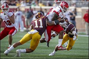 Miami, Ohio, running back Davion Johnson, middle, rushes between Minnesota defensive back Antoine Winfield Jr. (11) and Minnesota defensive back Antonio Shenault in Saturday's game in Minneapolis.
