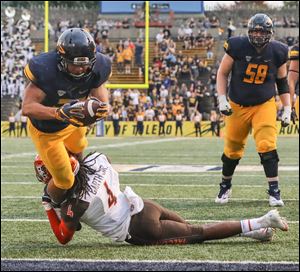 Toledo running back Bryant Koback scores a touchdown Saturday as Bowling Green defender Fred Garth tries to hang on.