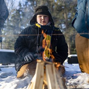 Malachi Lewis, 13, of Troop 123, watches the fire the troop built slowly burn the a line of rope to pass a stage during the Klondike Derby at Camp Miakonda.