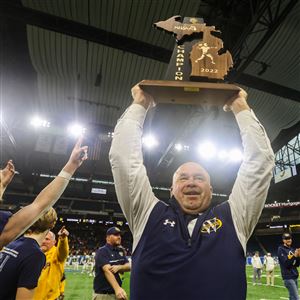 Whitefordu2019s head coach Todd Thieken holds up the MHSAA trophy as he celebrates their 26-20 win over Ubly in the Division 8 high school football state championship at Ford Field in Detroit on November 25.