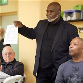 Former Mayor Mike Bell holds up the groups 12-point plan speaks during the Coalition For Peaceful Toledo Neighborhoods meeting at Park Church in Toledo on Saturday.