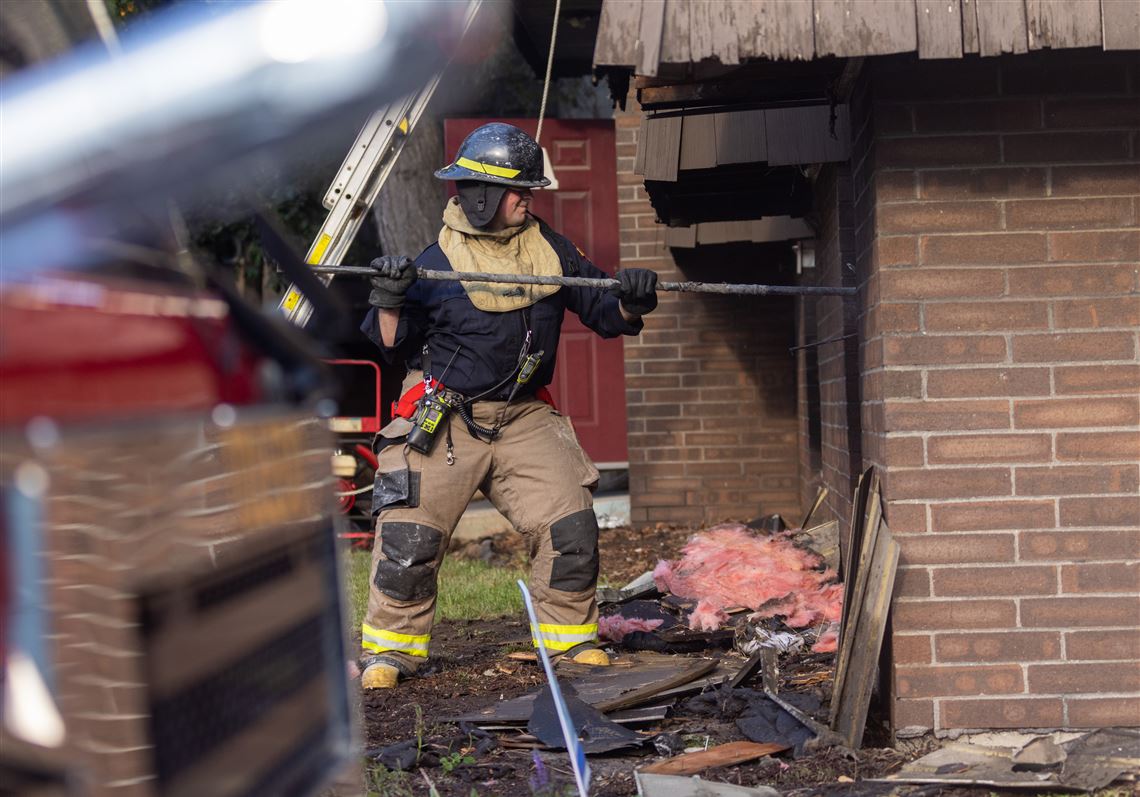 A firefighter breaks down a window in the first floor/subbasement level where a fire started at the Cedars Apartment buildings, June 3 in Toledo.