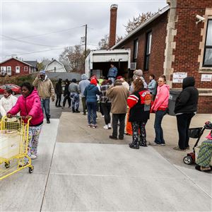 Toledo resident Zyrah,11, pushes a cart with a Thanksgiving meal box, turkey and pie after attending a giveaway on Nov. 20, 2023 at Helping Hands of St. Louis inToledo. 