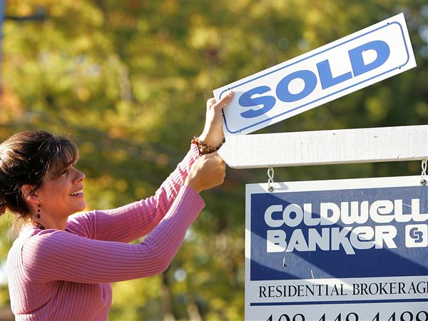 Coldwell Banker realtor Suzanne Hunter puts a sold sign on a home that she sold in Santa Clara, Calif., in 2007. 