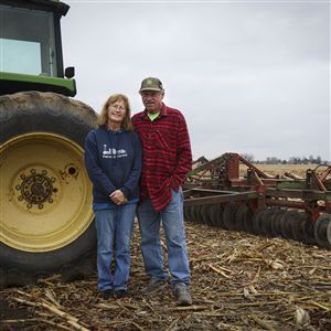 Donna and Mark Farnsel, fourth-generation owners of Farnsel Farms, stand beside a digging tractor as their corn lies harvested in Metamora on Nov. 21.