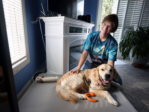 Jamie Osborn with her 11-month-old golden retriever Aziraphale, a service dog in training, at her home in Perrysburg.