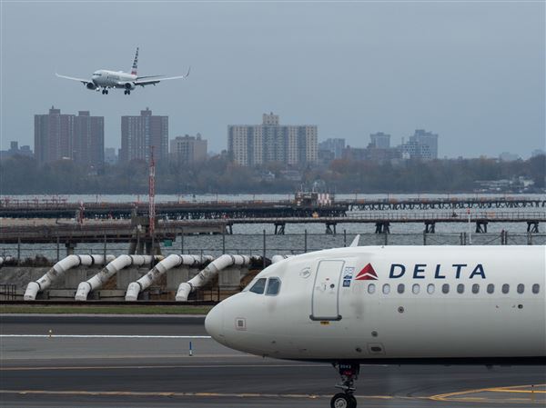 An American Airlines flight lands as a Delta Air Lines plane taxis at LaGuardia Airport (LGA) in the Queens borough of New York on Nov. 9.
